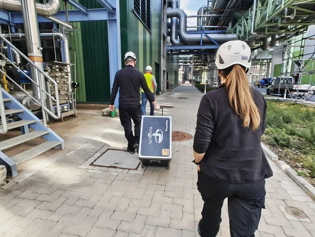 Kopterflug-teamet drar drönarväskan över ett kraftverksområde till uppdraget
