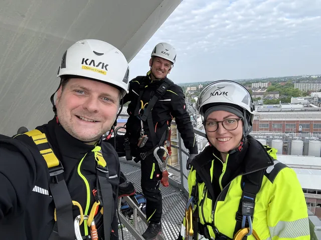Kopterflug-teamet med hjälm och fallskydd på en plattform ovanför ett industriområde
